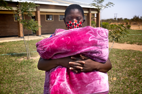 Image of Ireen with face mask holding blanket. 