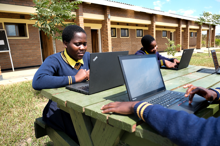 Image of Kuwala students outside with their newly donated laptops from Canada.