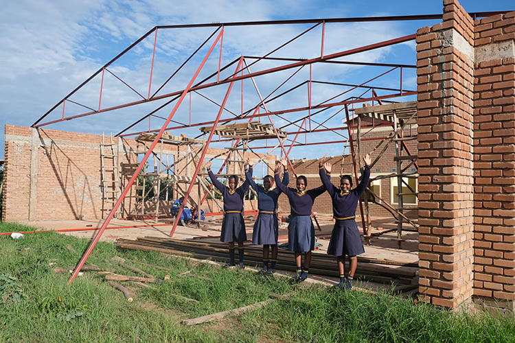 Image of raising the rafters in the Kuwala campus dining hall with girls underneath rafters.