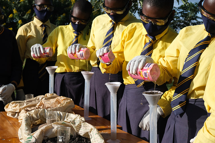 Image of Kuwala students testing soil outside using new lab equipment.