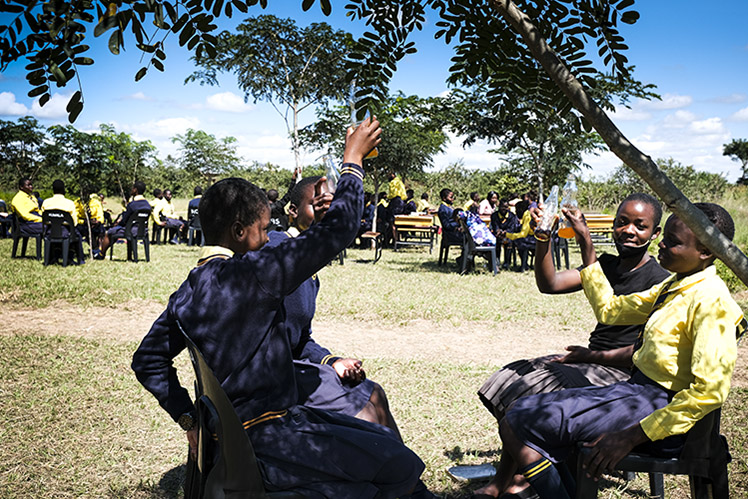 Image of Kuwala students outside in the shade enjoying a soft drink.