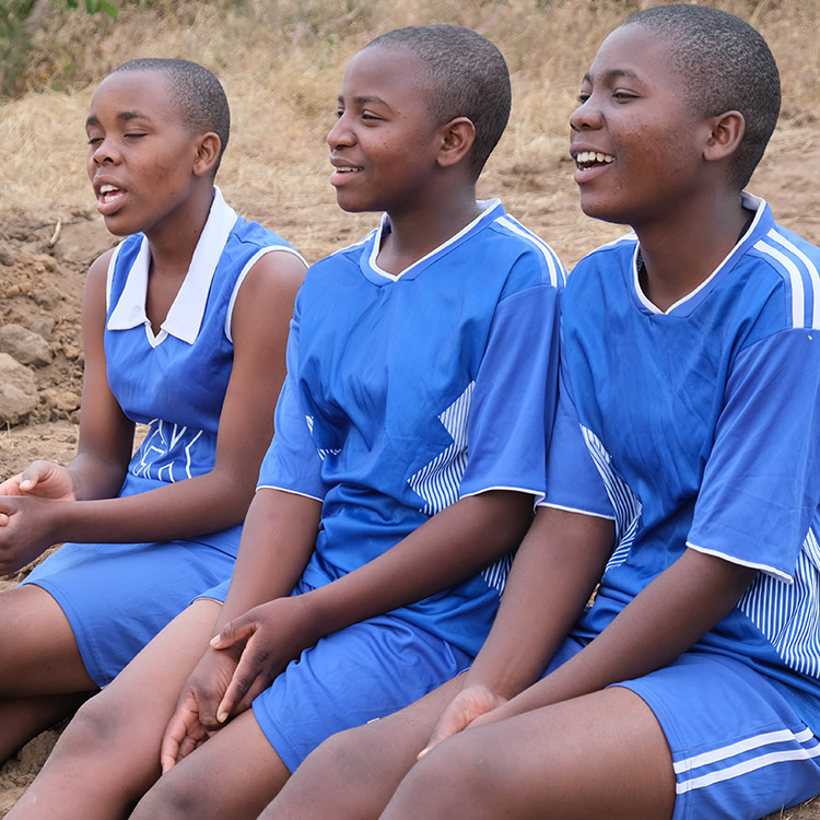 Image of Kuwala girls on the side line watching the soccer game unfold.