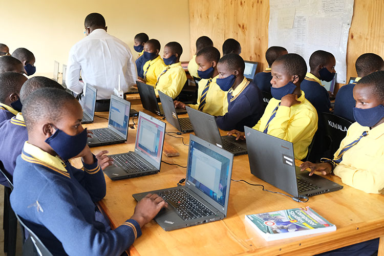 Kuwala students studying with computers and workbooks