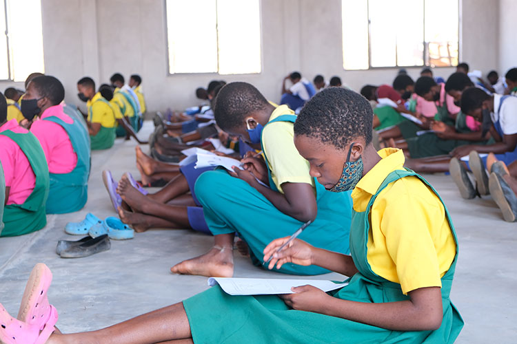 Potential Kuwala student candidates writing the exam on the floor of St. Peter's Assembly Hall.