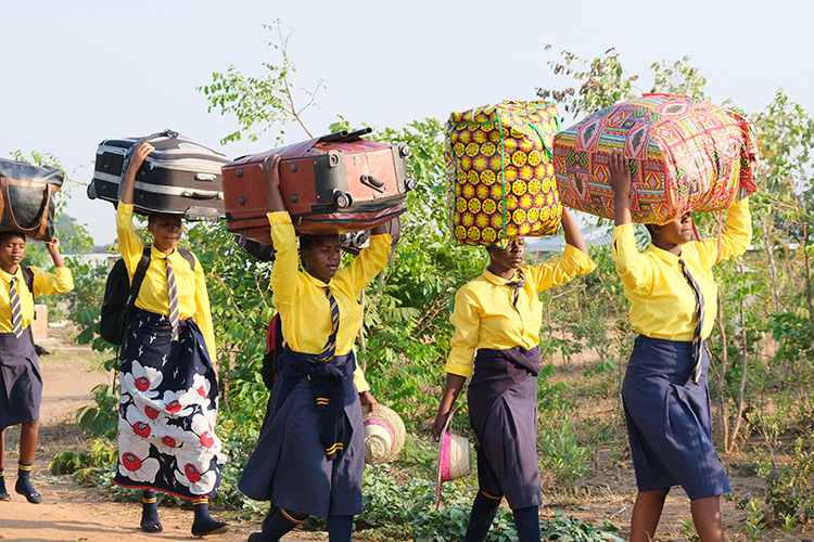 Kuwala students carrying very colourful patterned luggage balanced on their head. Colourful bags must be a Malawi thing. 