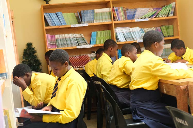 Kuwala students in uniforms studying in the library.