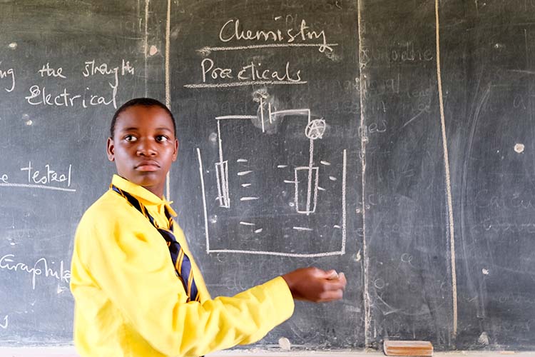 Kuwala student showing chemical reaction on blackboard. 