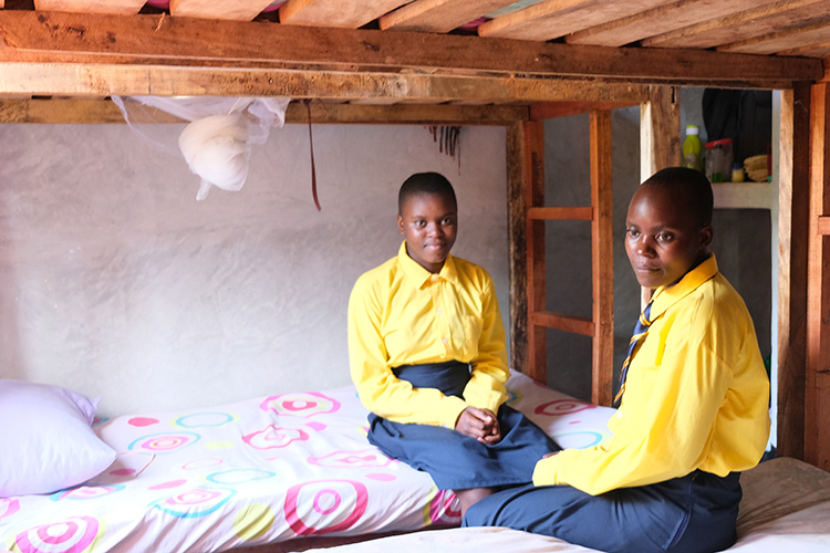 Two Kuwala girls setting on new mattress and bunk bed