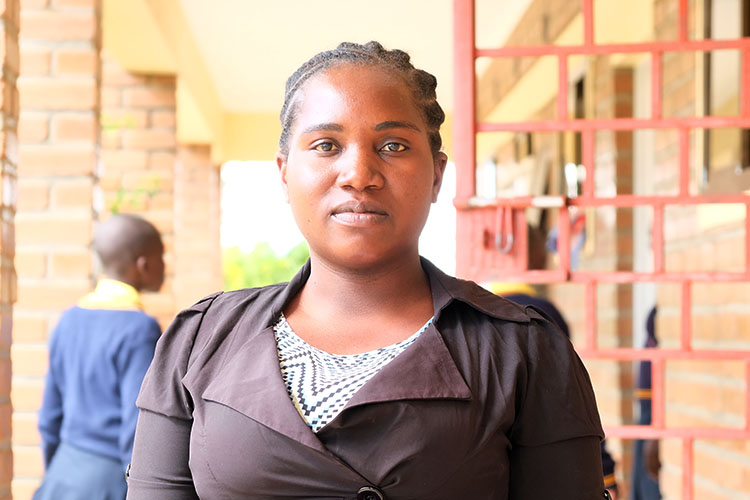 Kuwala teacher, Christina Mkumbwa outside Classroom Block one.