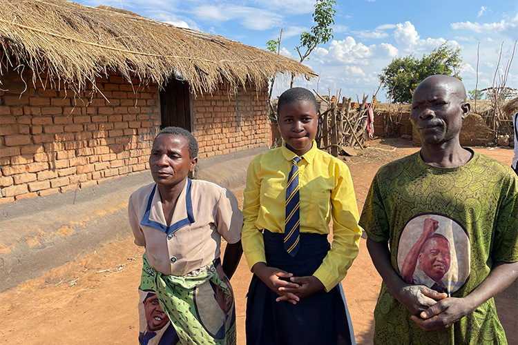 Malawian family outside their thatched grass roof