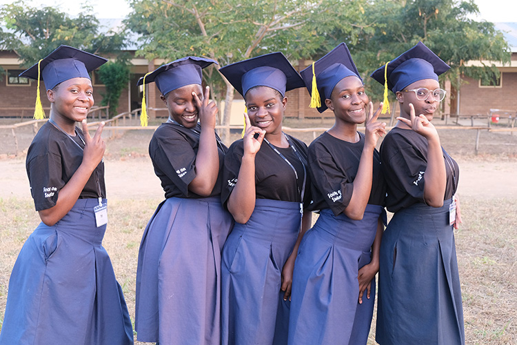 Kuwala grad group of girls posing outside the classroom block.