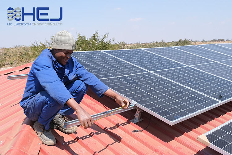 Technician on the roof of a Kuwala building installing solar panels. 