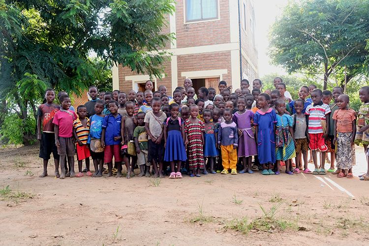 Group of local children from Malawi village in front of the Kuwala water tower. 