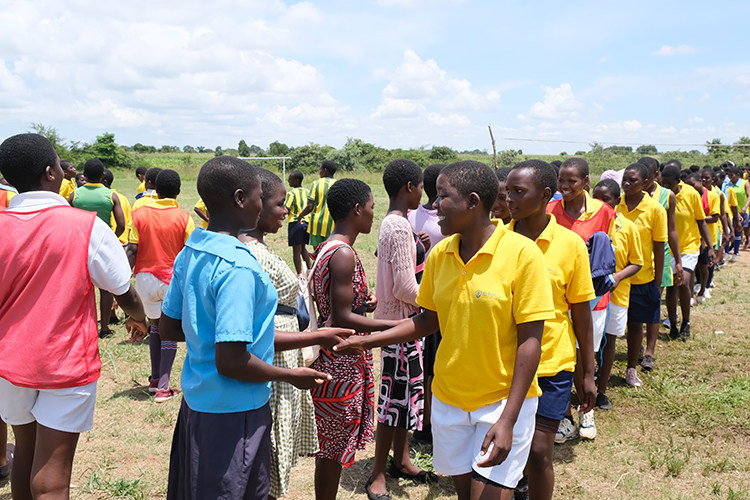 Groups of students in two lines shaking hands. 