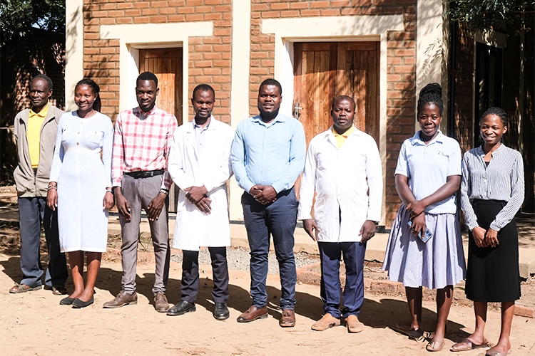 Kuwala teachers in front of the water tower building on a bright sunny day.
