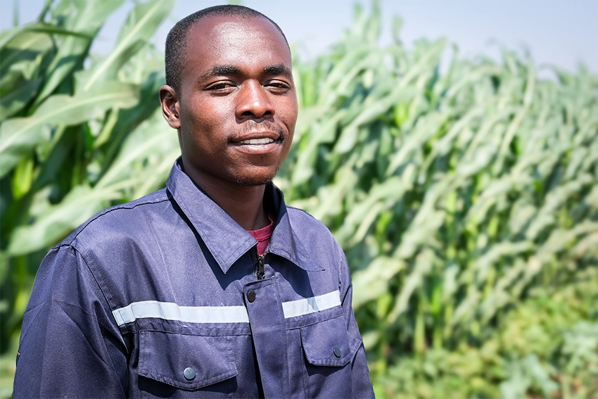 Patrick the new Kuwala farm manager in front of a row of tall plants in the background.