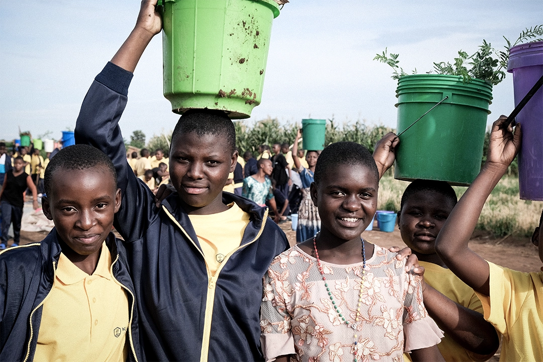 Kuwala students and villagers outside in the foreground a Kuwala student is carrying an bucket on her head.