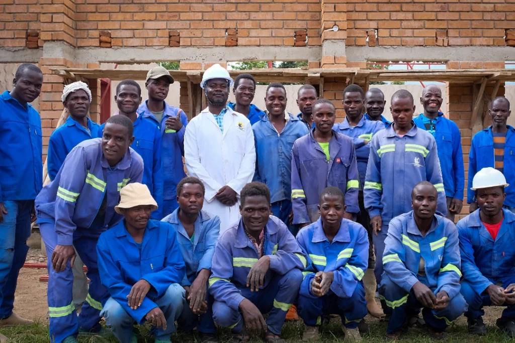 Building contractor team 5 in front of Kuwala classroom block being built in the background.