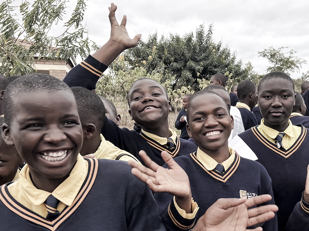 Students outside all smiles and waving. 